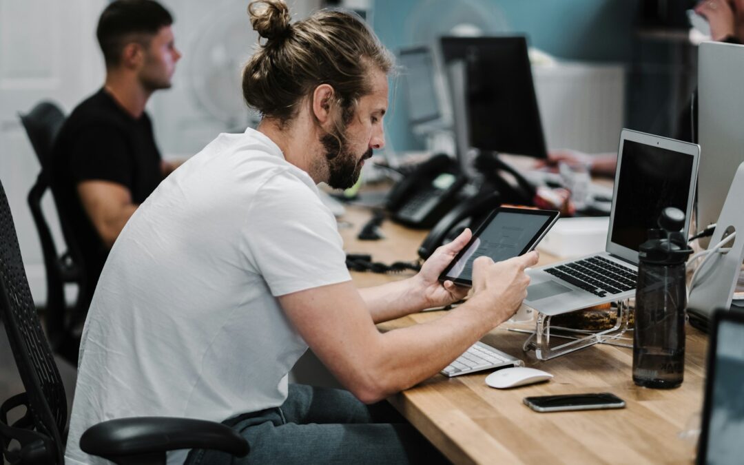 man holding turned-on iPad in front of turned-off MacBook Air